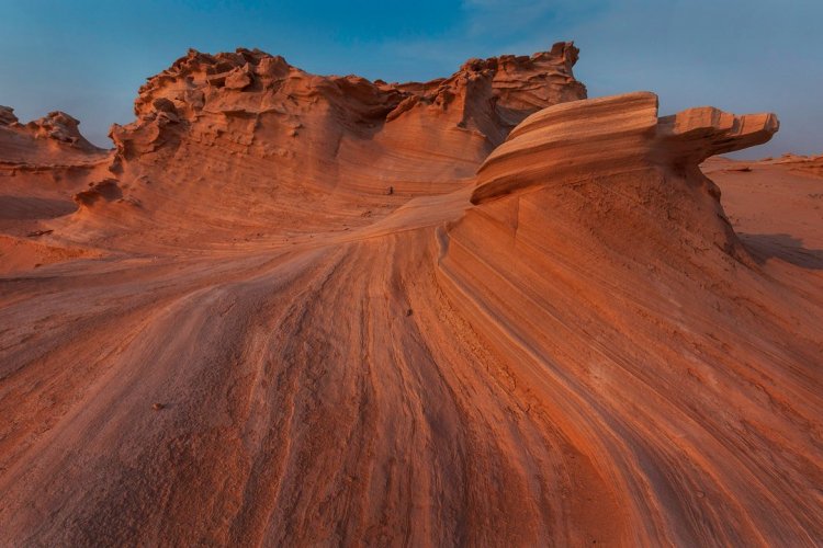 6. S’émerveiller devant les dunes fossiles d’Al Wathba Le désert du Rub al Khali, ou « quart vide », constitue la plus vaste étendue de sable ininterrompue au monde. Il est aussi au cœur de la culture et de l’histoire d’Abu Dhabi, témoin de traditions intemporelles comme la fauconnerie ou l’élevage de chameaux. Véritable paysage de dunes ocres se déployant à l’infini, le désert d’Abu Dhabi se caractérise par son relief, certaines de ses dunes comme celle de Tel Moreeb dépassant les 300 mètres de haut. Mais pour découvrir une véritable curiosité naturelle, il faut se rendre dans la portion de désert autour d’Al Wathba. Différant du sable meuble et des courbes changeantes de la crête des dunes, le désert d’Abu Dhabi abrite aussi des formations de sables durcies, érodées et façonnées petit à petit par les vents. Les dunes fossiles d’Al Wathba se présentent ainsi comme un champ de figures fossilisées aux formes uniques et étonnantes, qui peuvent rappeler par certains côtés le sud-ouest américain. Pour profiter d - © visitabudhabi