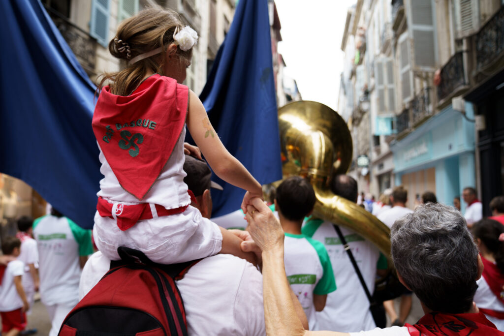 Petite fille sur les épaules de ses parents aux Fêtes de Bayonne