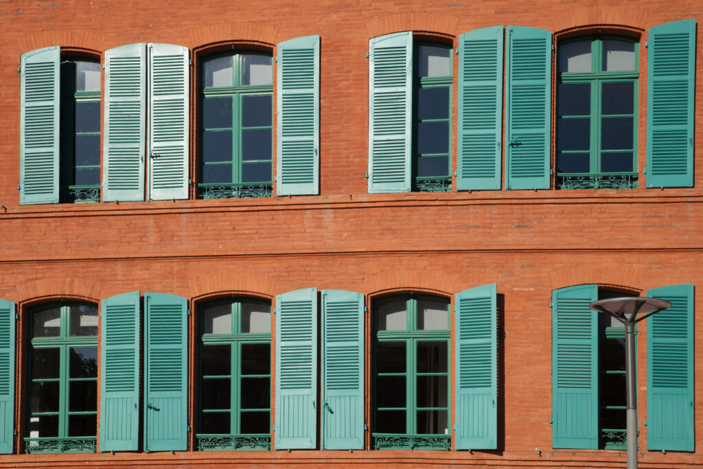 Façade de briques aux volets verts dans la ville de Montauban