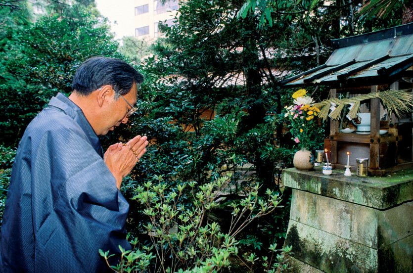 Homme d'affaires se recueillant devant l'autel d'Inari, le dieu du riz et patron des commerçants.