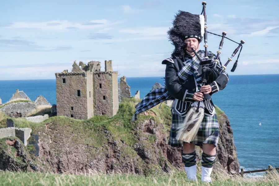 Joueur de cornemuse devant Dunnottar Castle. Lukassek - iStockphoto.com