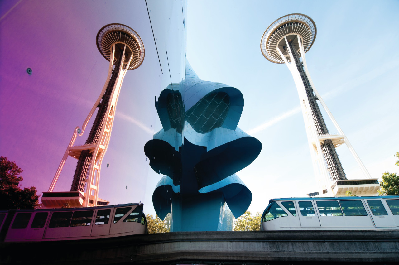 Seattle, USA - September 19, 2013 : The Seattle Monorail entering the Seattle Center through the Experience Music Project with a reflection of the Space Needle on a sunny day. The Monorail was originally built in 1962 for the Worlds Fair.