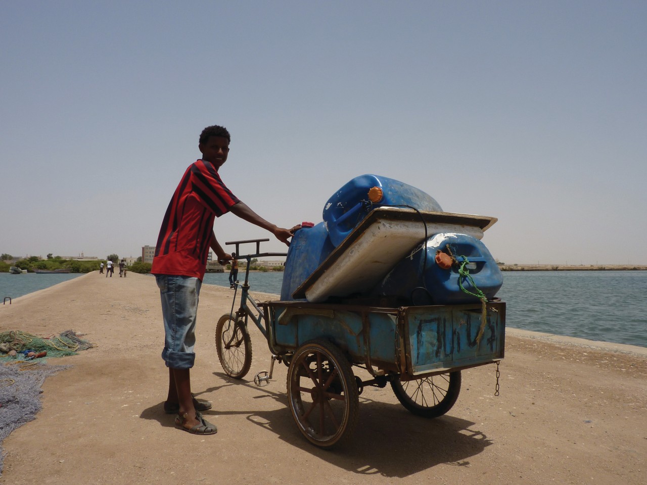 Jeune garçon transportant des bidons d'eau douce, sur l'île de Taulud.